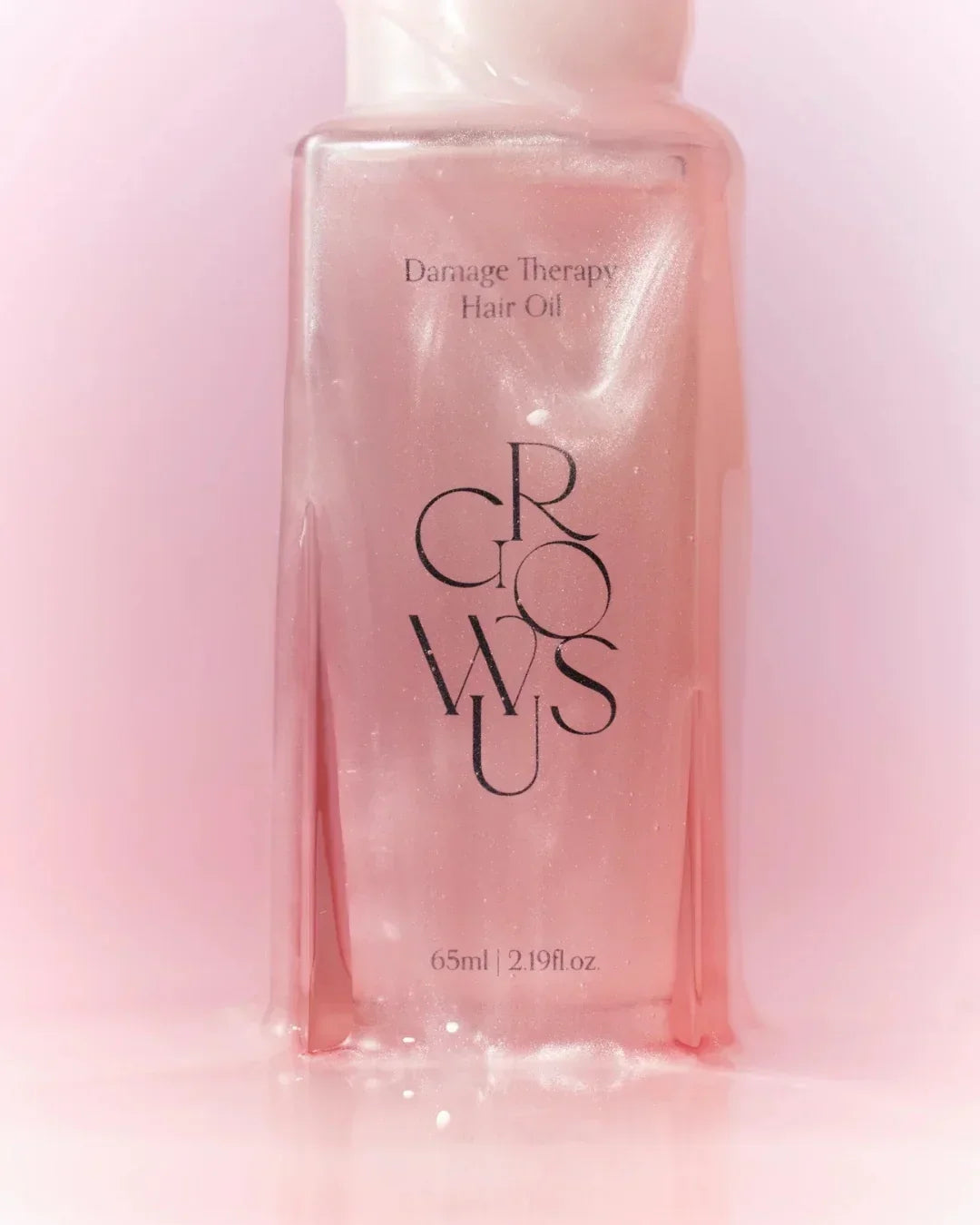 Shimmering pink Damage Therapy Hair Oil bottle with 65ml capacity on soft pink background