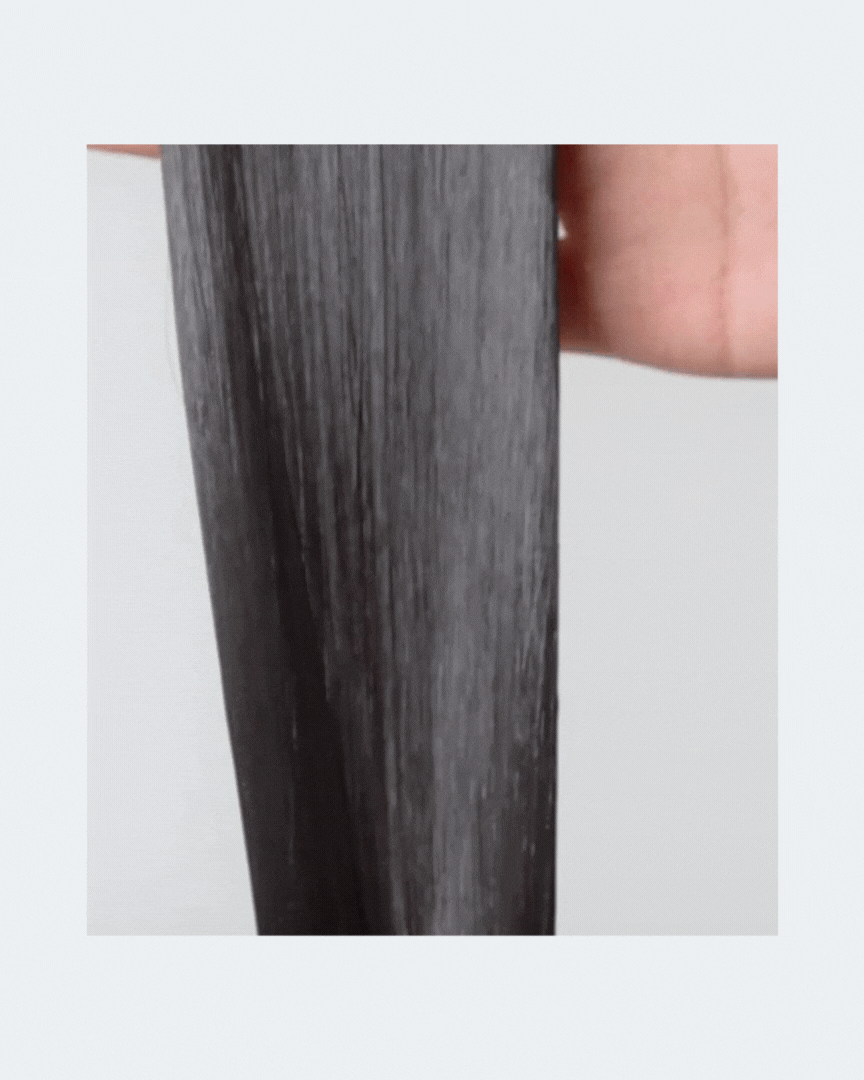 Hand holding smooth, shiny black hair strand after damage therapy hair treatment