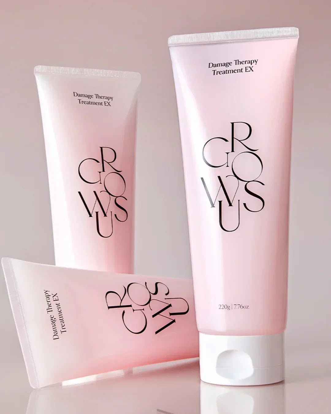 Three pink tubes of Damage Therapy Treatment EX hair care product with white caps on a reflective surface