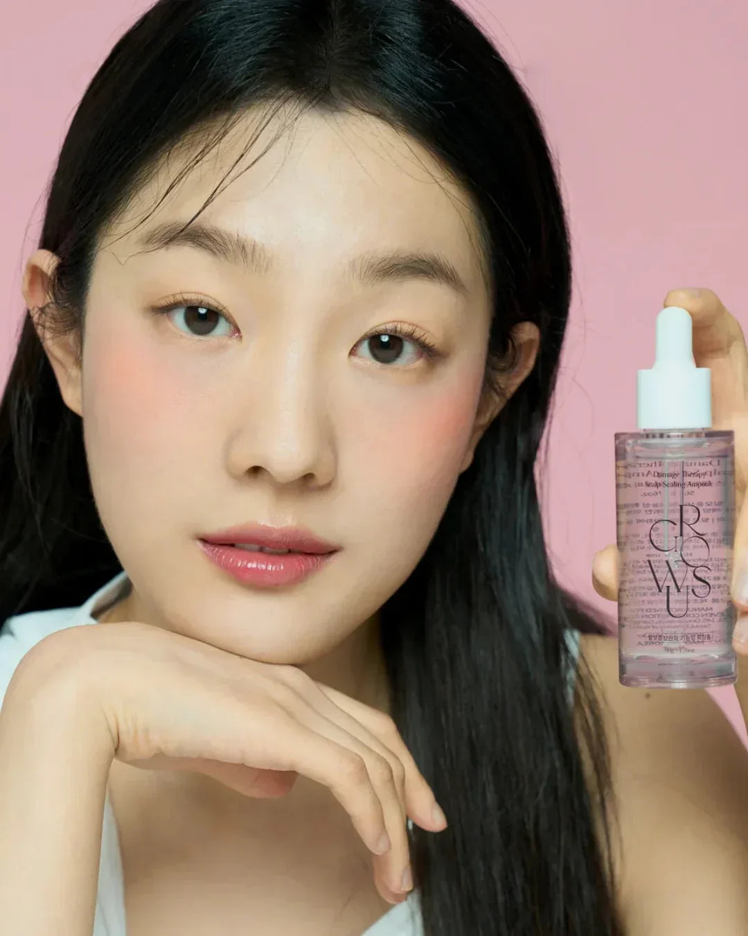 Young woman with clear skin holding scalp scaling ampoule skincare product against pink background