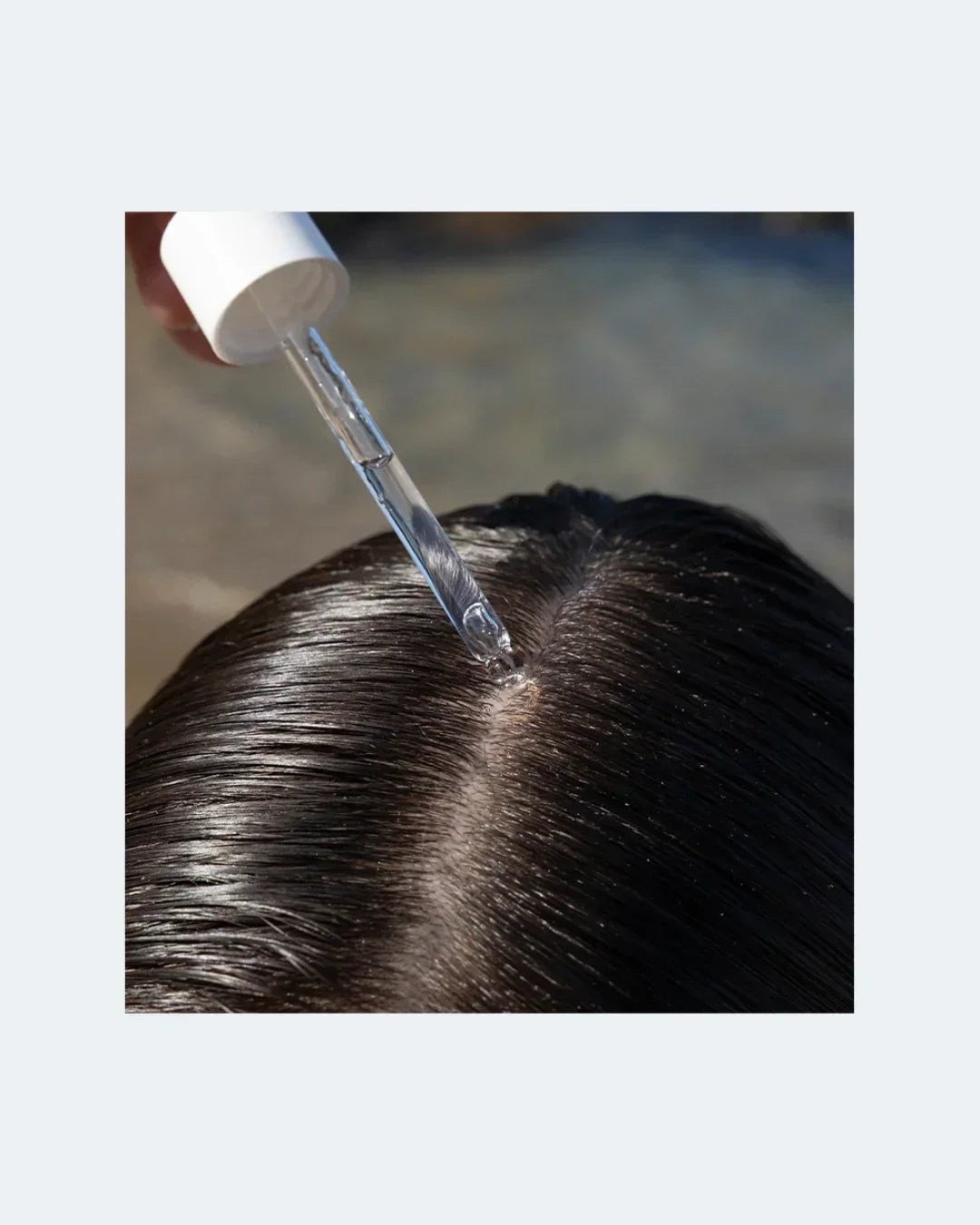 Close-up of clear scalp serum dropper applying hair treatment to healthy scalp