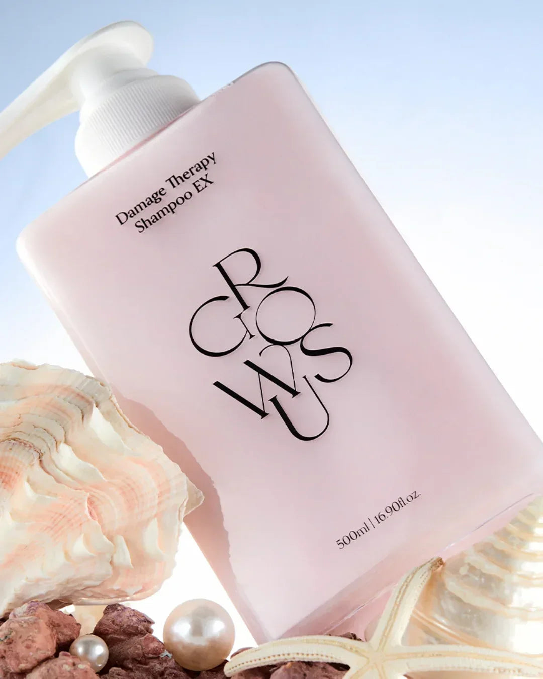 Pink 500ml Damage Therapy Shampoo EX bottle with seashells and pearls on light background