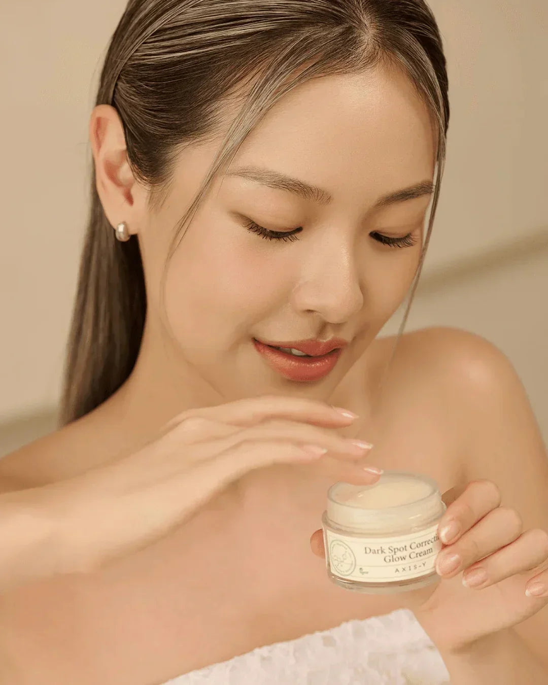 Woman applying Dark Spot Correcting Glow Cream from a jar for skincare and radiant skin