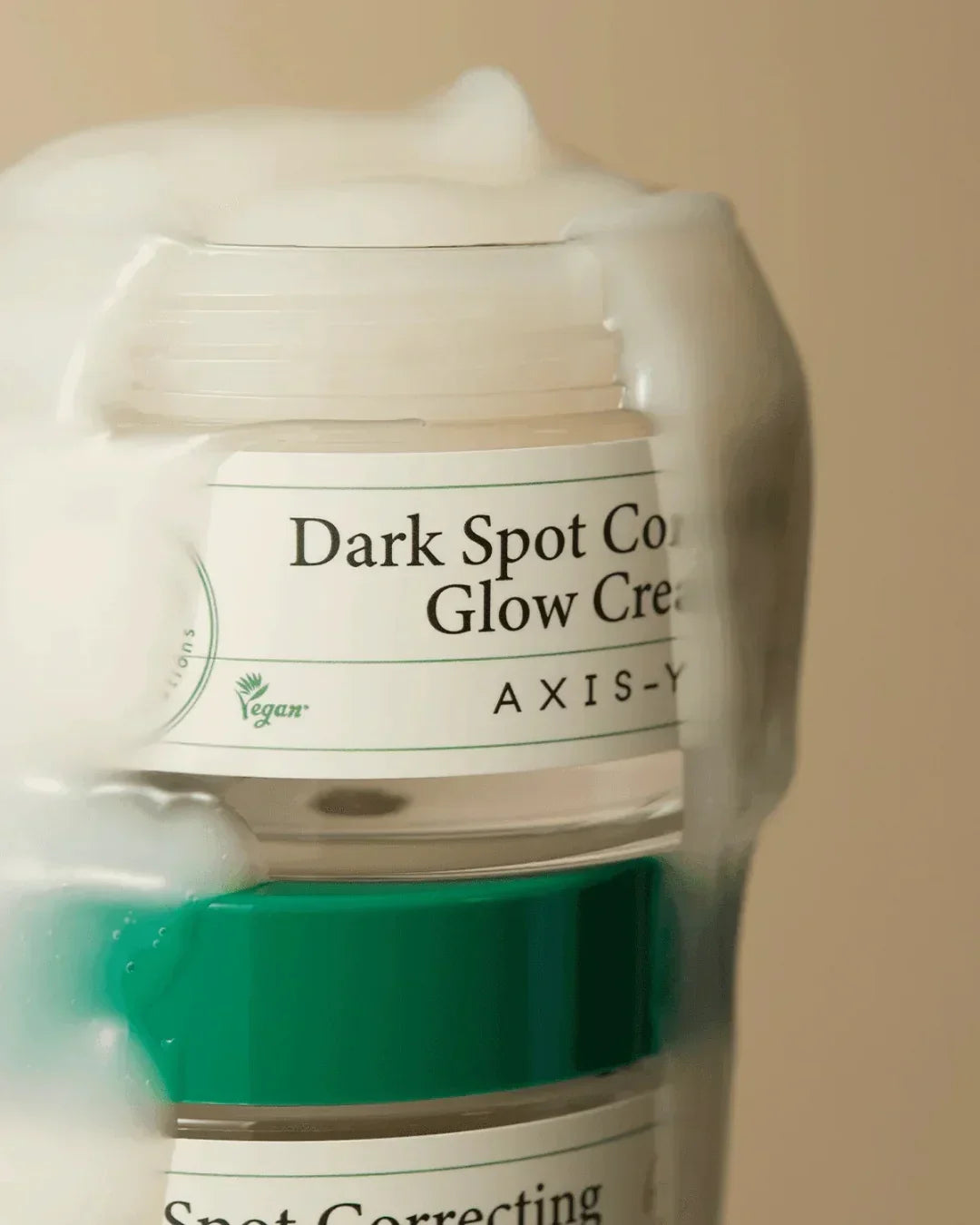 Axis-Y Dark Spot Correcting Glow Cream jar with creamy texture on beige background