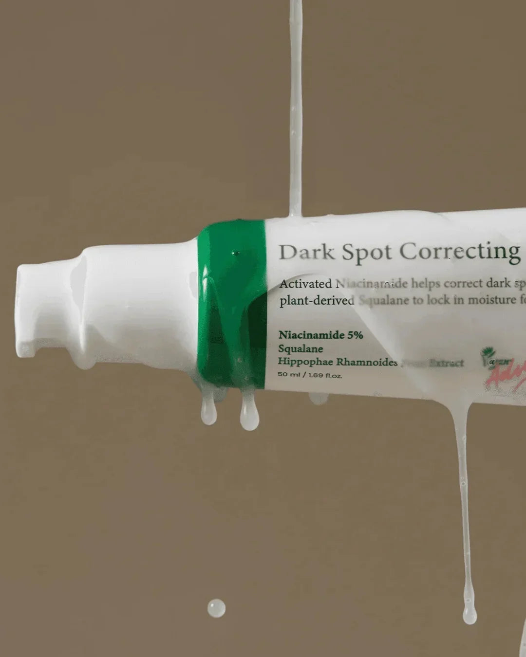 Dark Spot Correcting serum tube with white liquid dripping against a beige background