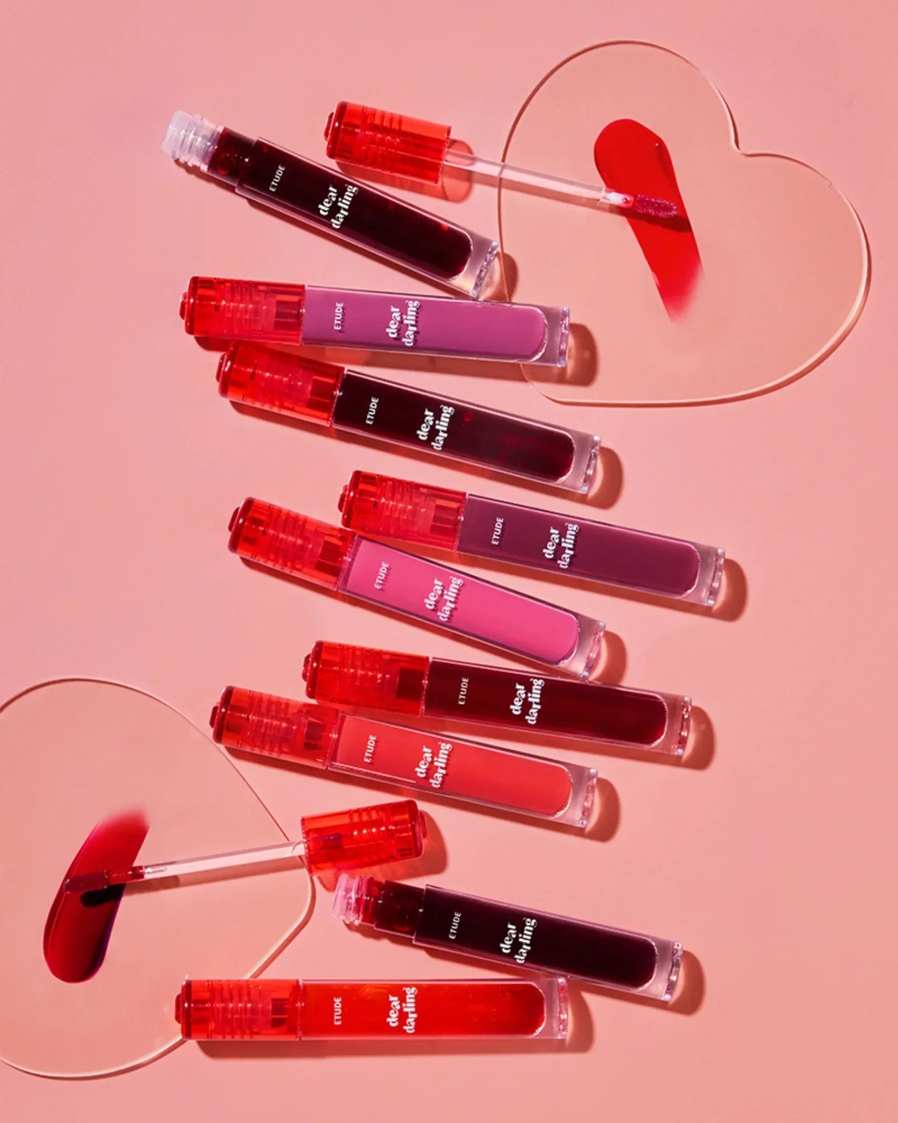 Etude Dear Darling Water Gel lip tints in various shades on pink background with heart-shaped swatches