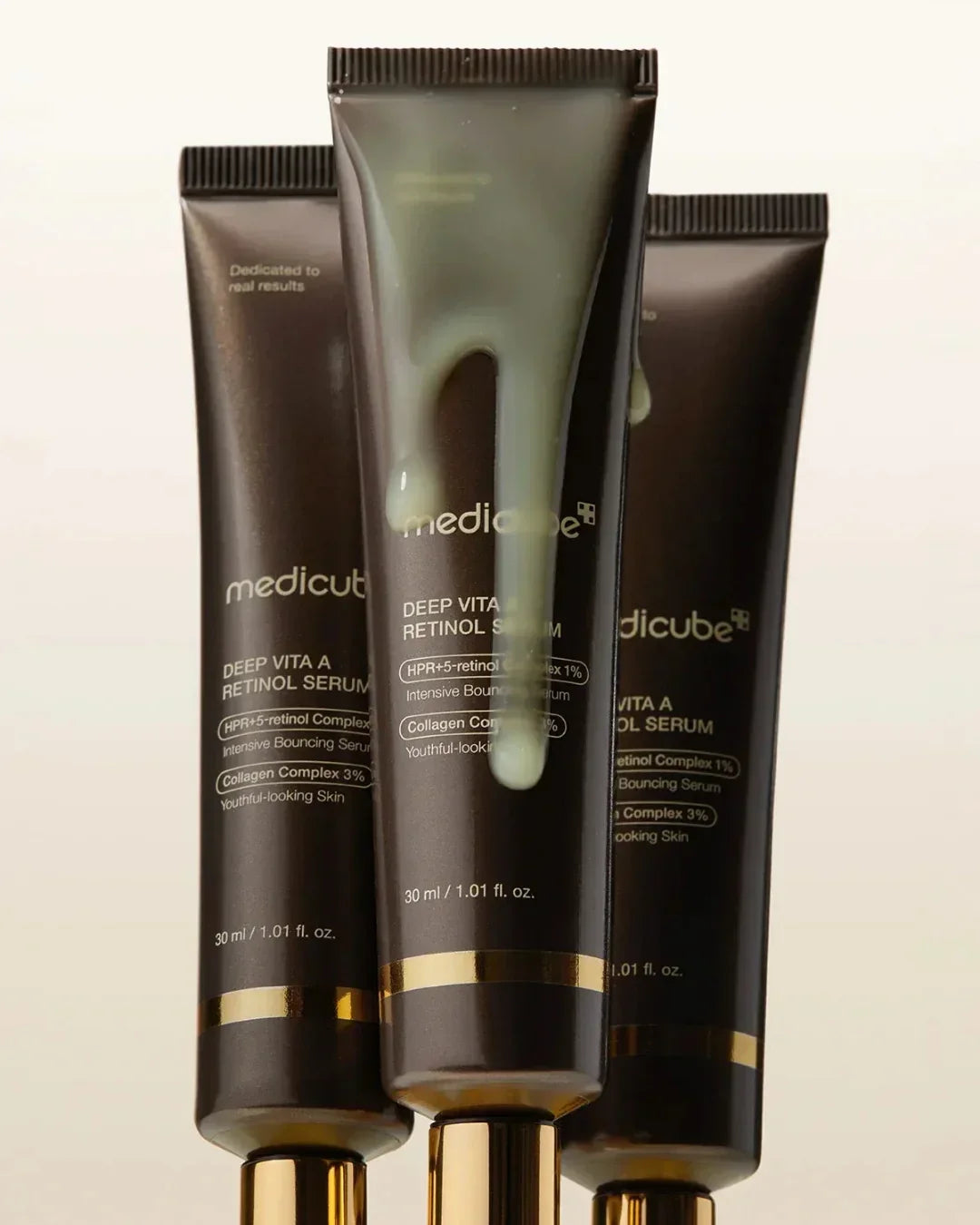 Three tubes of Medicube Deep Vita A Retinol Serum with golden caps and serum texture dripping