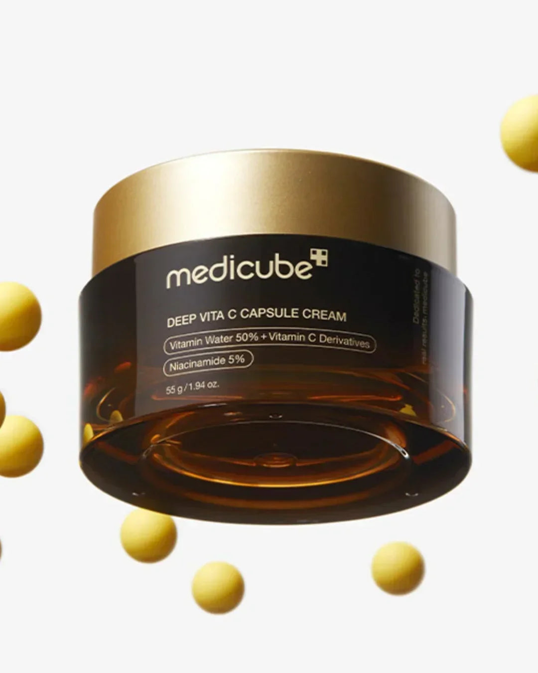 Medicube Deep Vita C Capsule Cream jar with gold lid and floating yellow capsules on white background