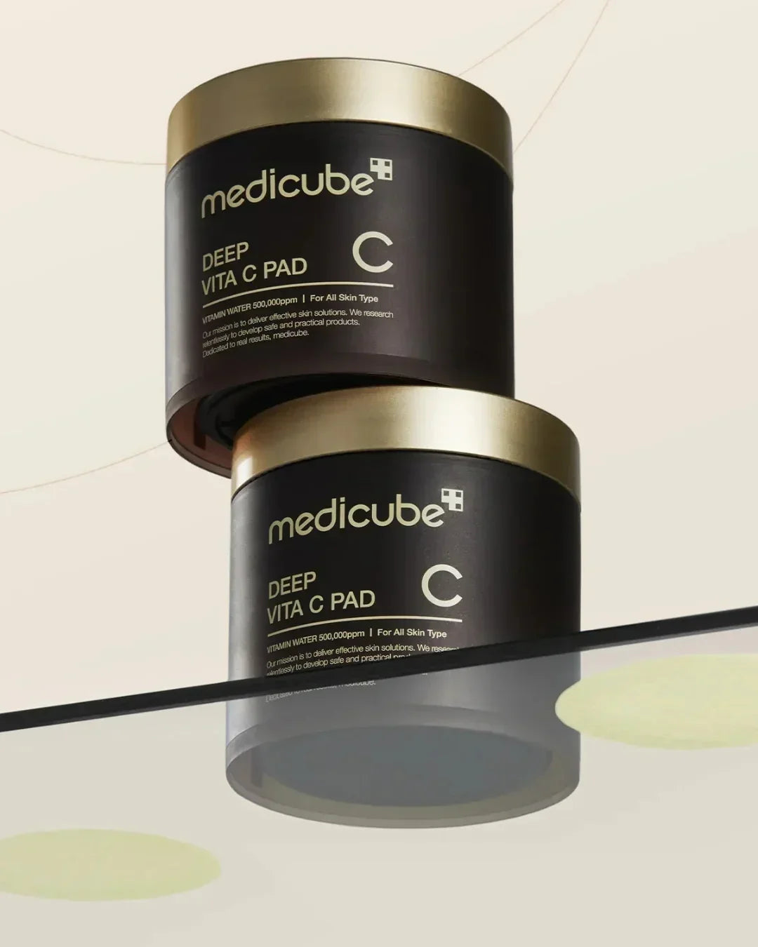 Medicube Deep Vita C Pad skincare containers with gold lids on reflective surface