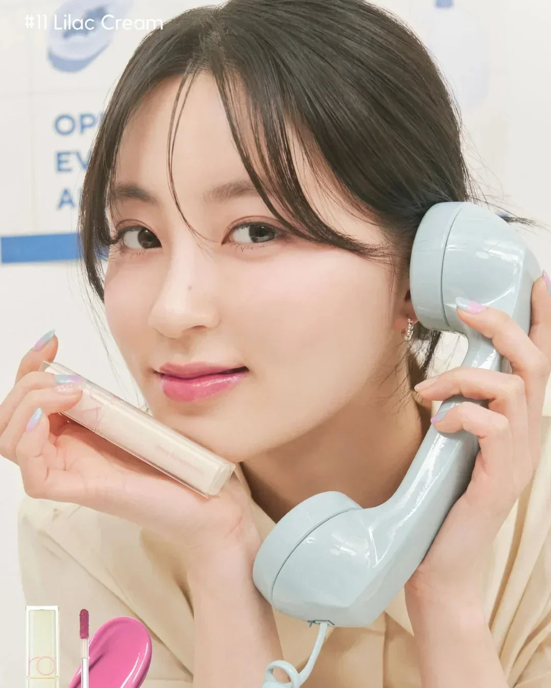 Young woman holding lilac cream lip tint and a retro blue telephone handset