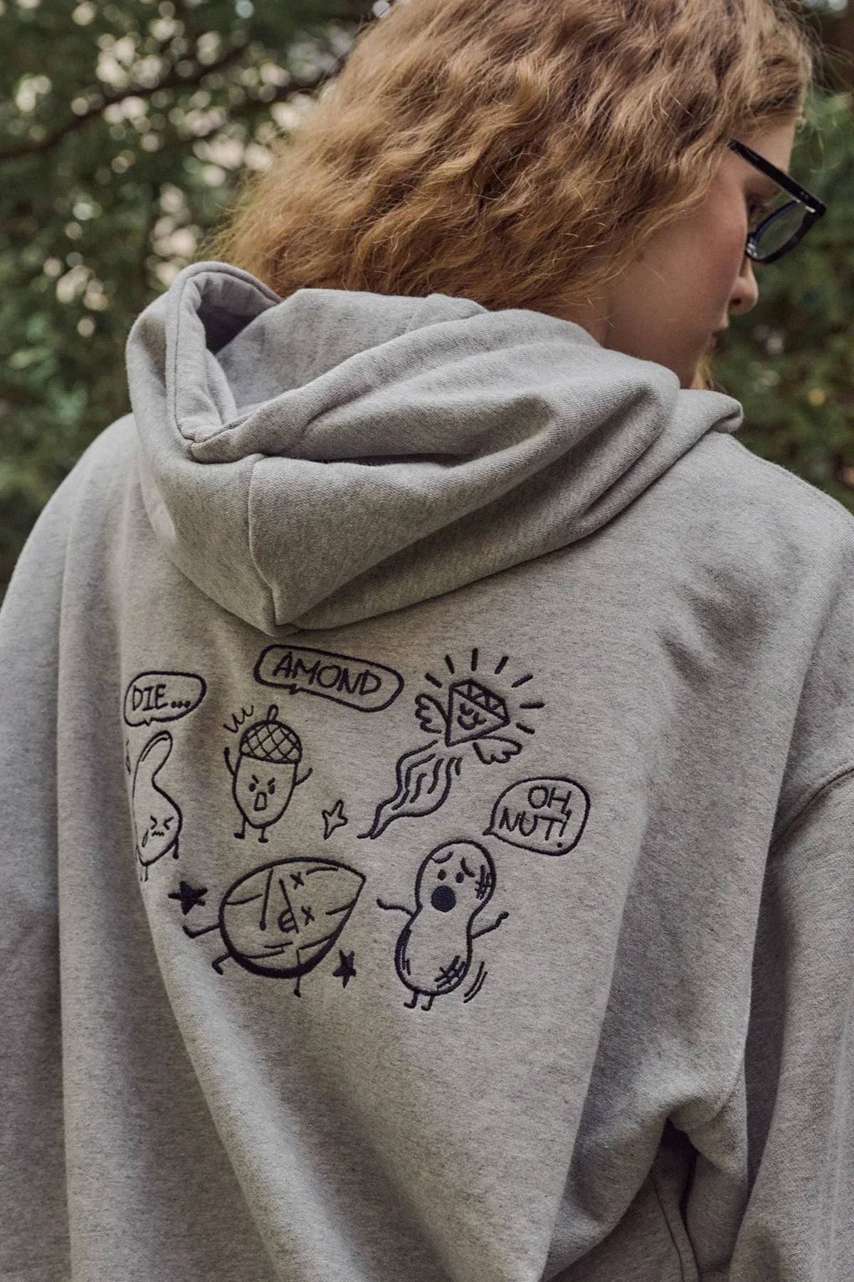 Close-up of gray hoodie with playful nut-themed doodles and speech bubbles on back