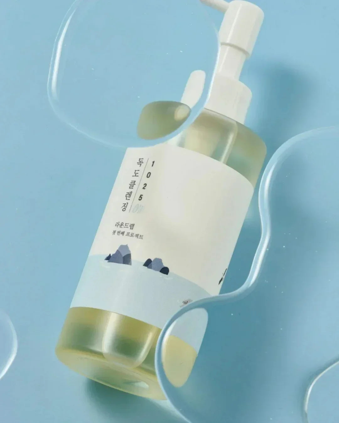 Dokdo cleansing oil 200ml bottle on blue background with water droplets, Korean skincare product
