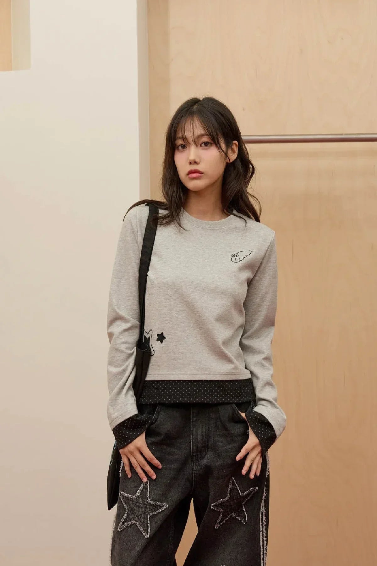 Young woman wearing grey long sleeve t-shirt with black star and cat appliques and black star embroidered jeans