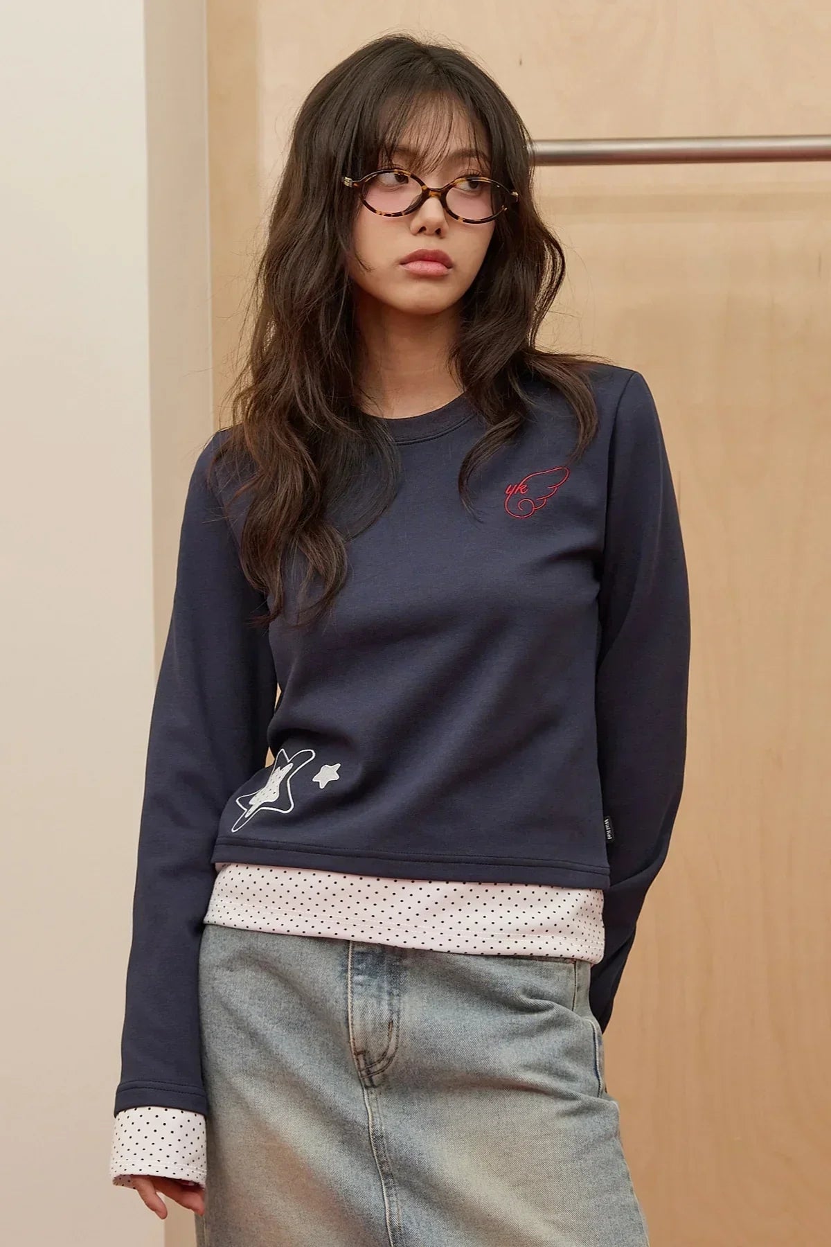 Young woman wearing navy dot applique layered long sleeve t-shirt with polka dot cuffs and denim skirt