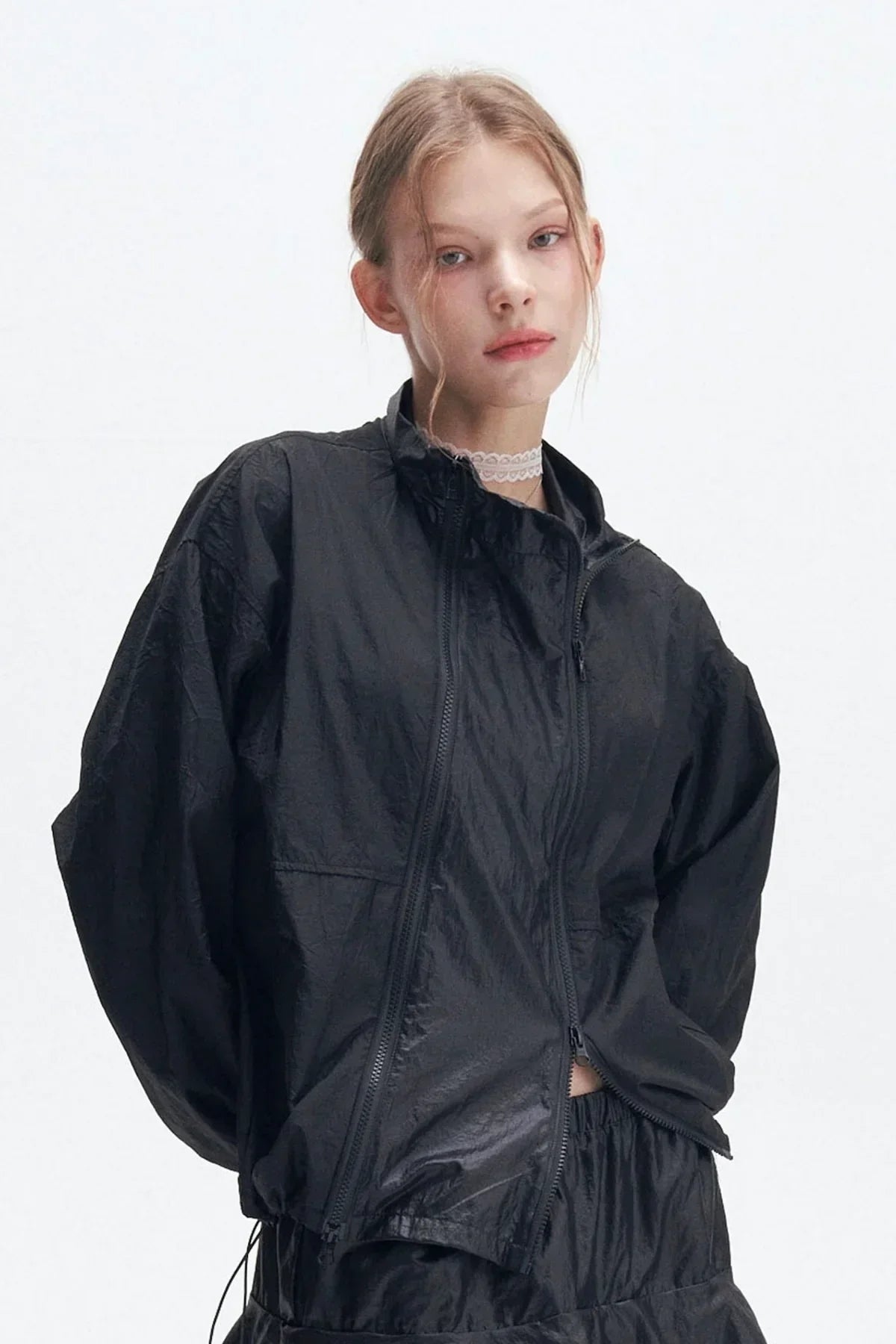 Young woman wearing black double zipper windbreaker jacket with high collar in studio