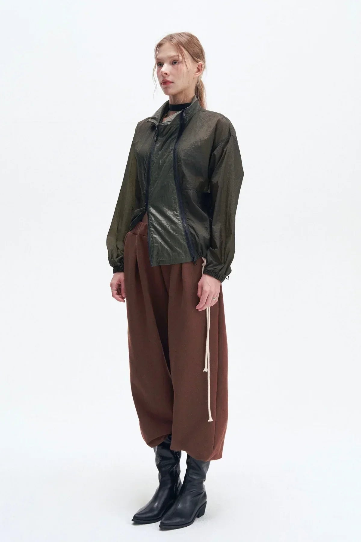 Woman wearing a double zipper khaki windbreaker jacket with brown wide pants and black boots