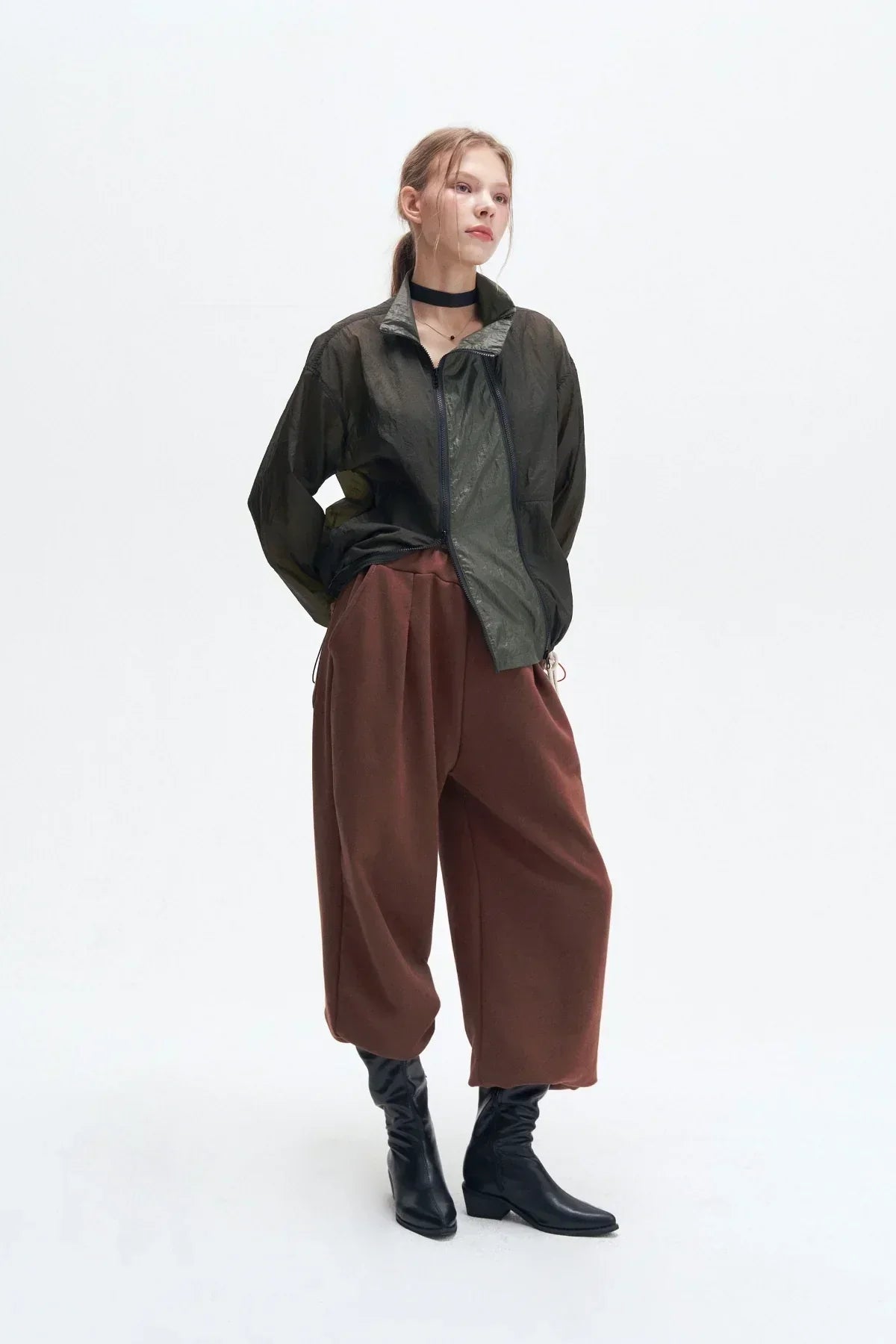 Model wearing khaki double zipper windbreaker jacket with brown wide pants and black boots