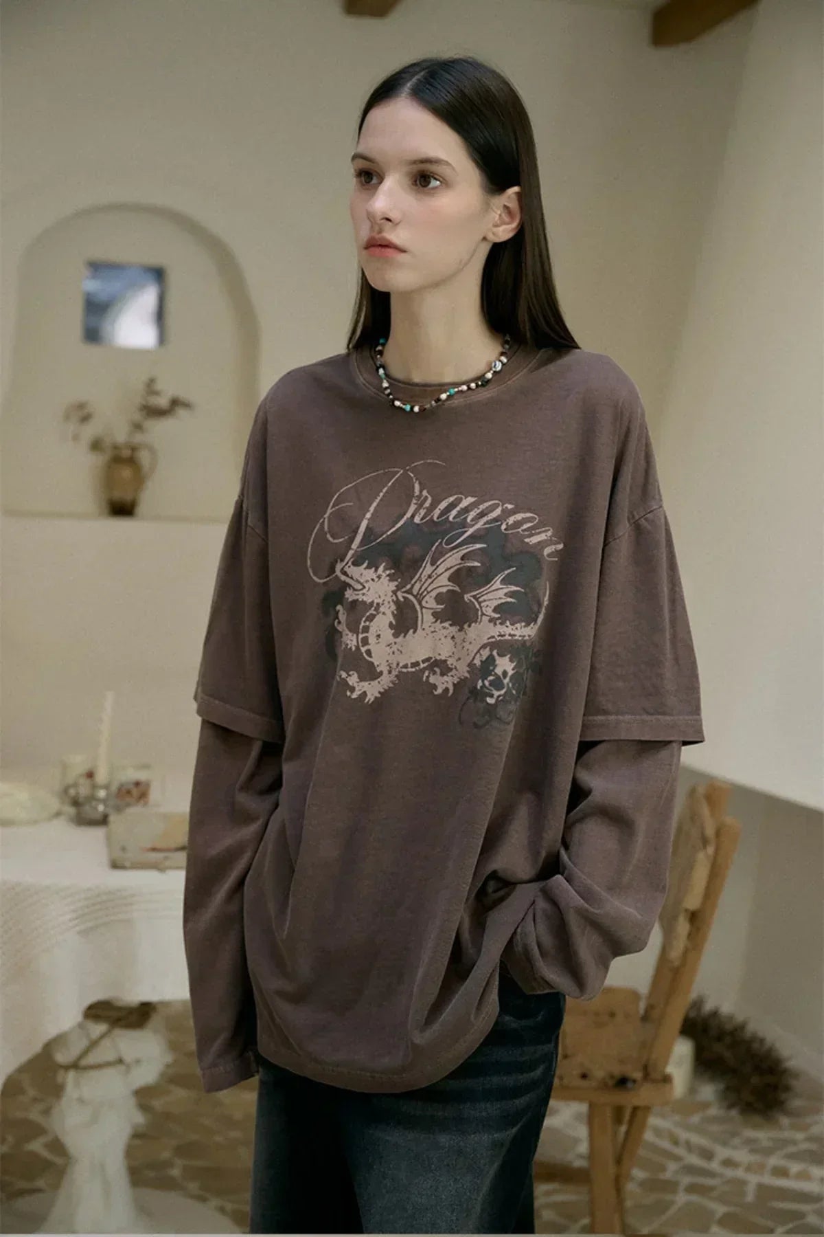 Young woman wearing brown dragon print layered long sleeve top in cozy indoor setting
