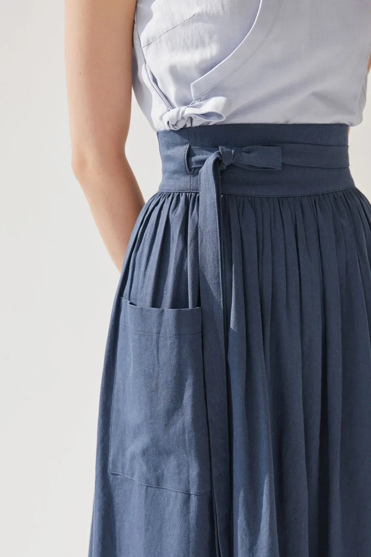 Close-up of navy blue denim skirt with tied waist belt and large side pocket