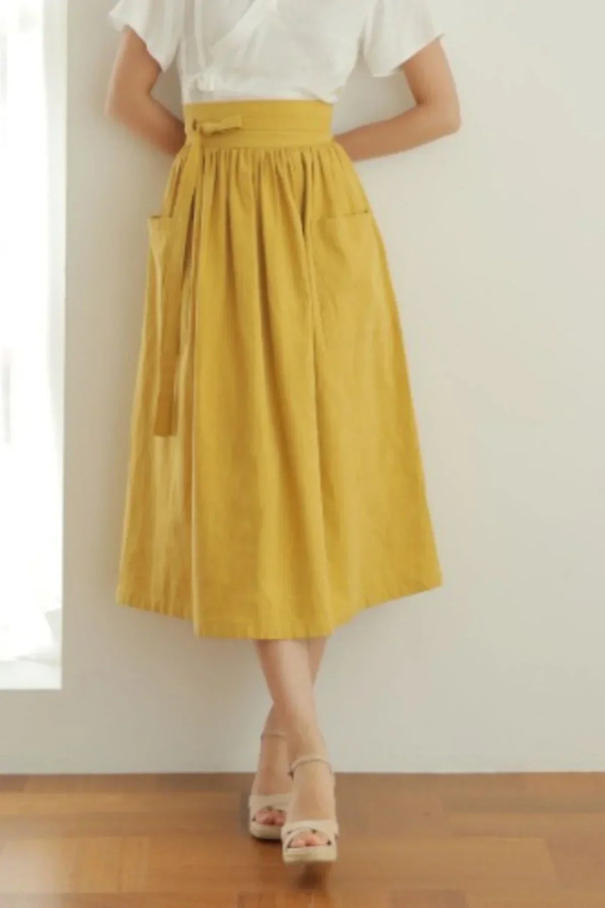 Woman wearing mustard yellow midi skirt with pockets and beige platform sandals indoors