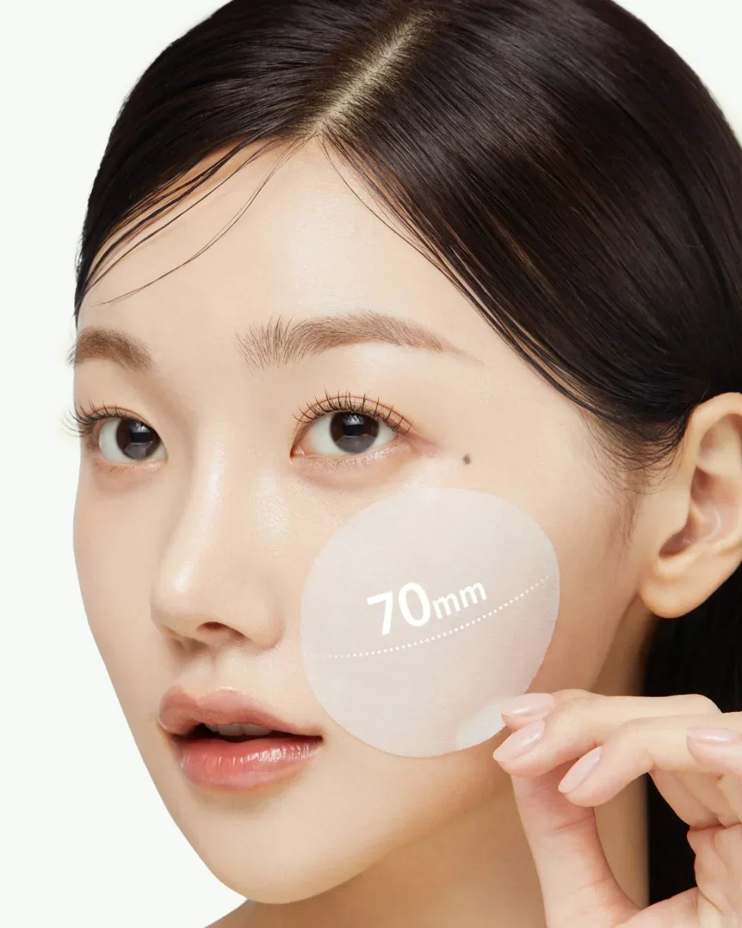 Close-up of a woman applying a 70mm exosome cica face pad to her cheek for skincare