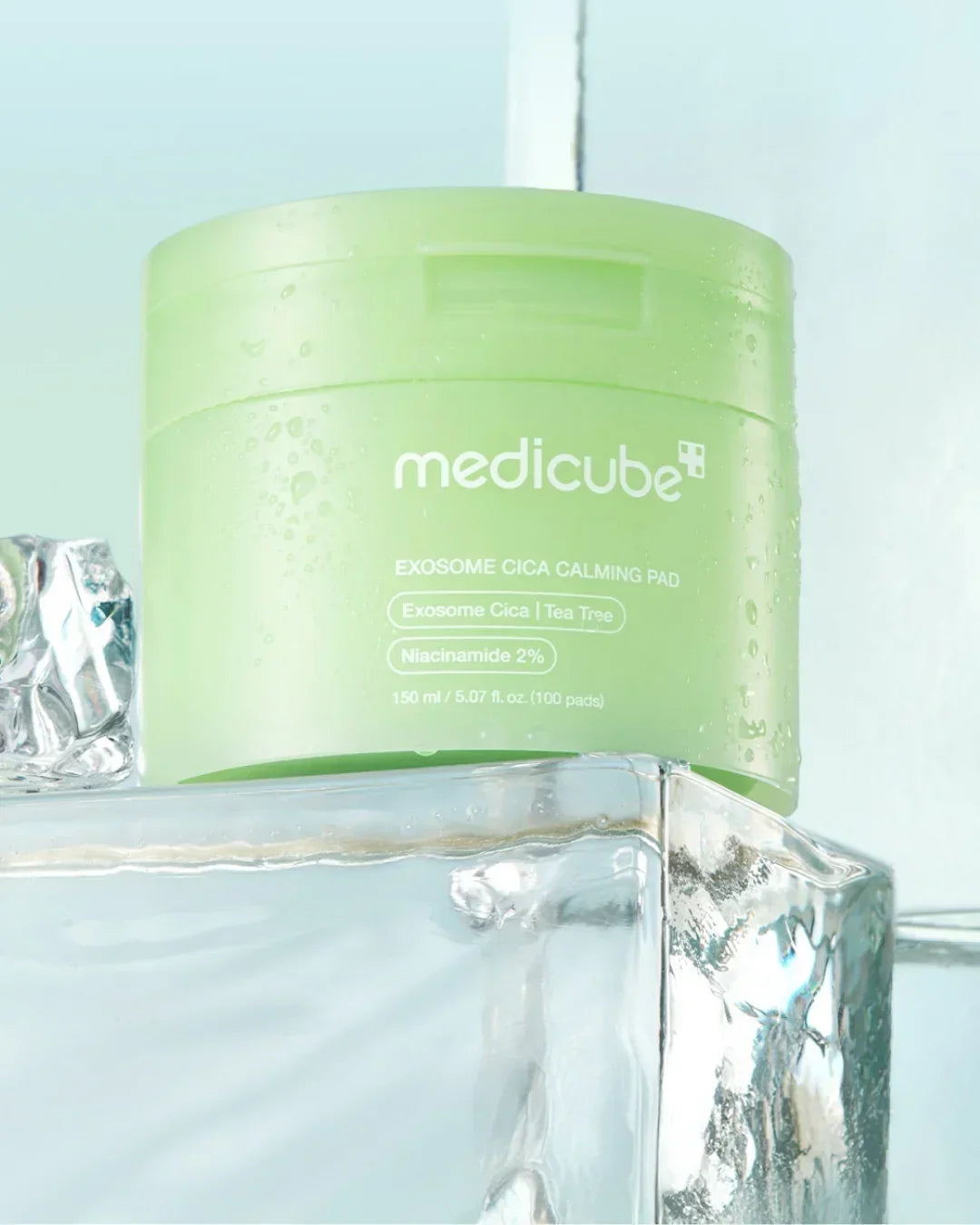 Green Medicube Exosome Cica Calming Pad container with water droplets on ice block