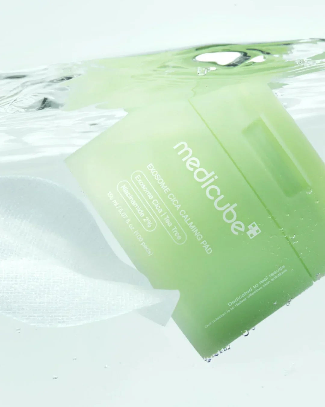 Green Medicube Exosome Cica Calming Pad container and pad submerged in clear water