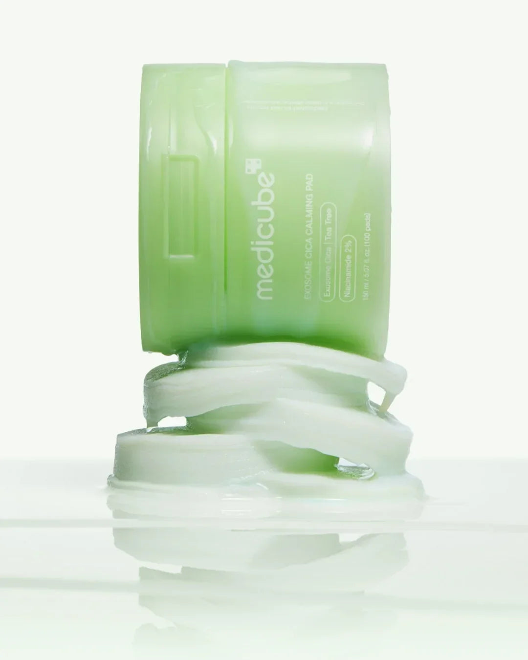 Green Medicube Exosome Cica Calming Pad container with stacked white cotton pads on white surface