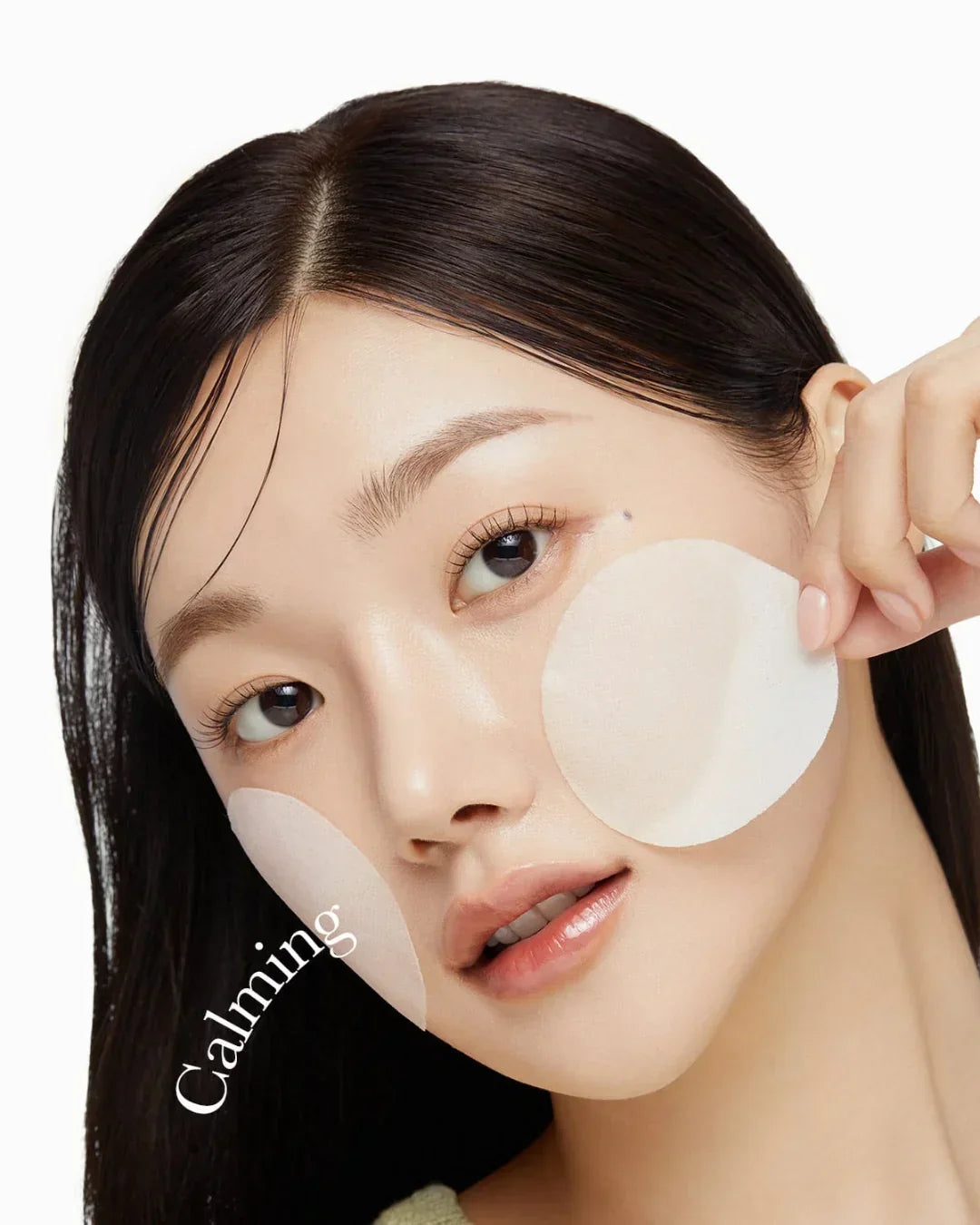 Close-up of woman applying round calming skincare patches to cheeks, highlighting soothing facial care