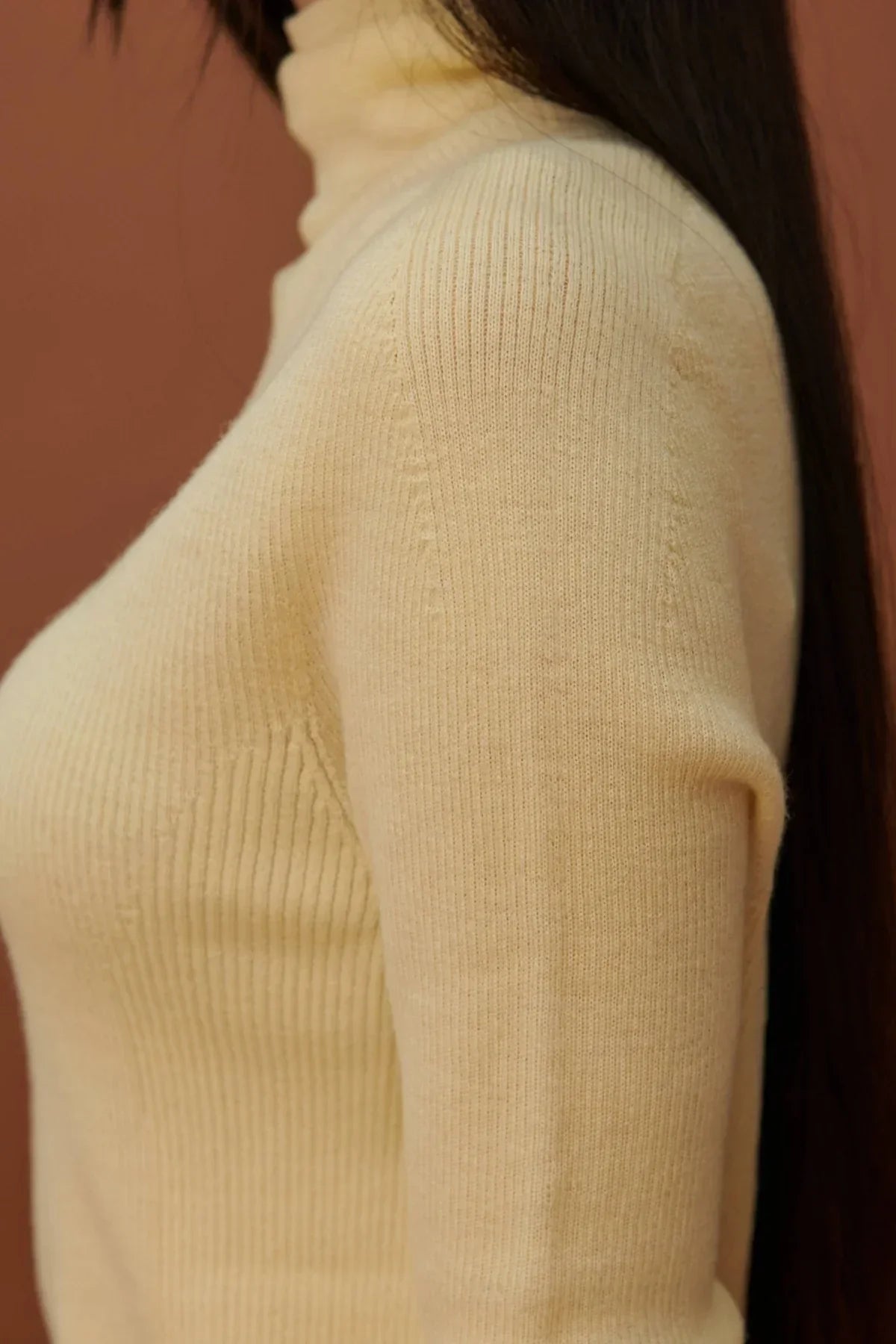 Close-up of a fine rib wool yellow turtleneck sweater on a woman with long brown hair