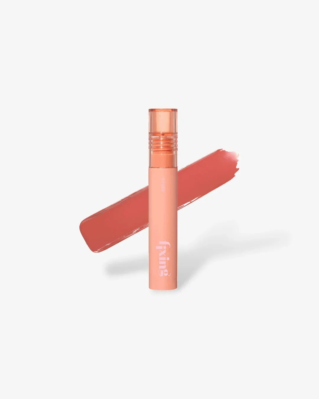 Peach-colored Fixing tint lip product with clear cap and peach lip color swatch on white background
