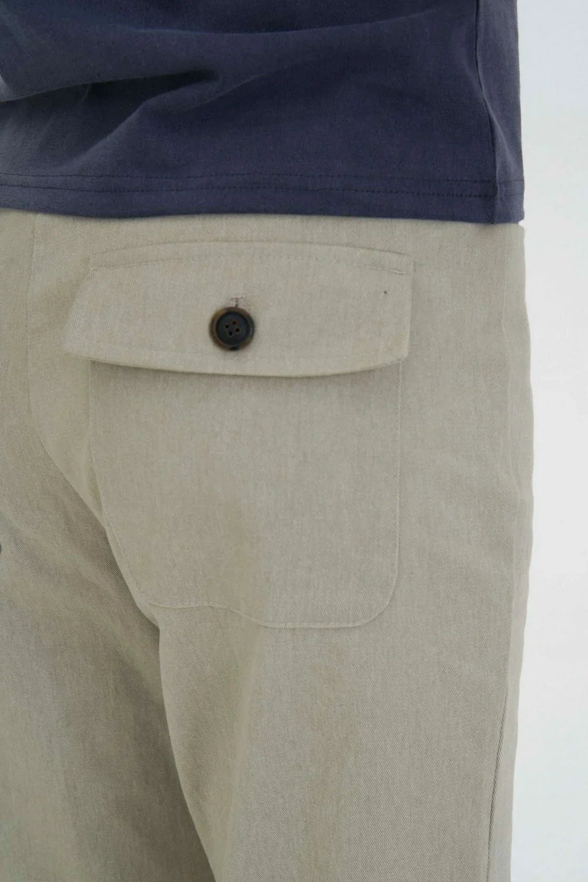 Close-up of beige flared cargo pants pocket with button detail and navy blue shirt
