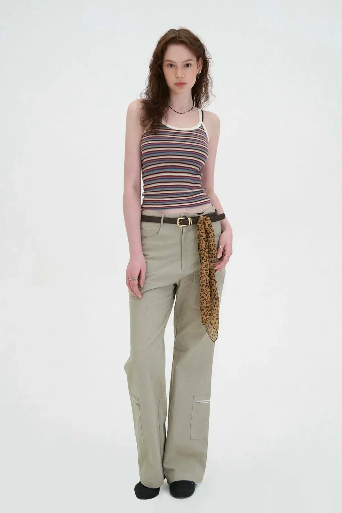 Young woman wearing beige flared cargo pants with side zippers and leopard print scarf on belt