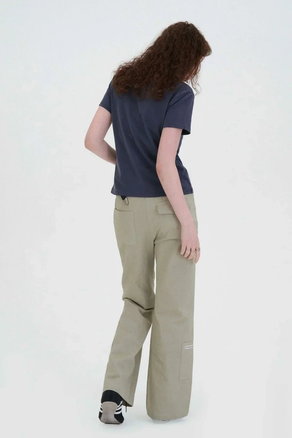 Woman wearing beige wide-leg cargo pants and navy t-shirt standing against white background