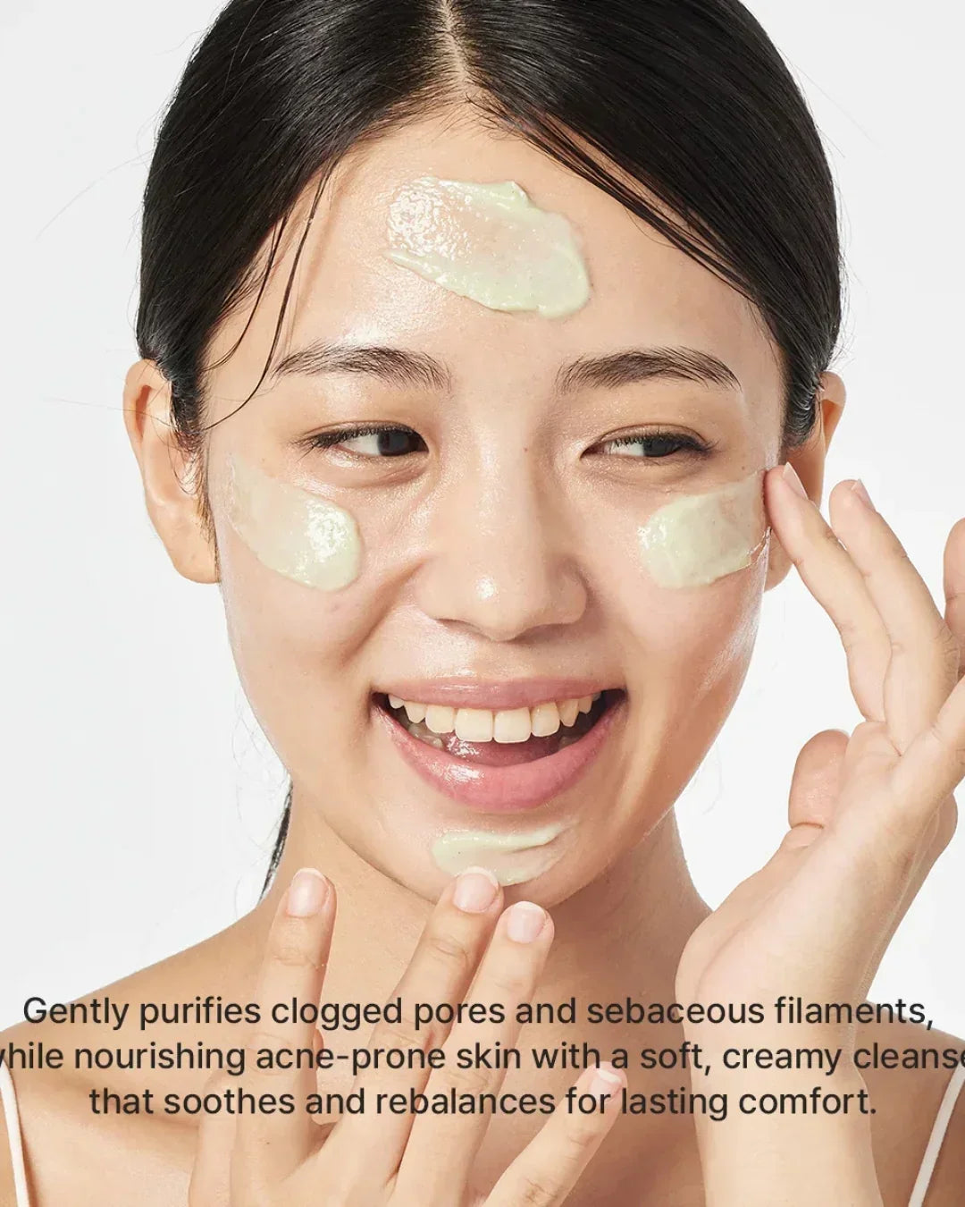 Close-up of woman applying fresh green rice mochi cleanser cream on face with smiling expression