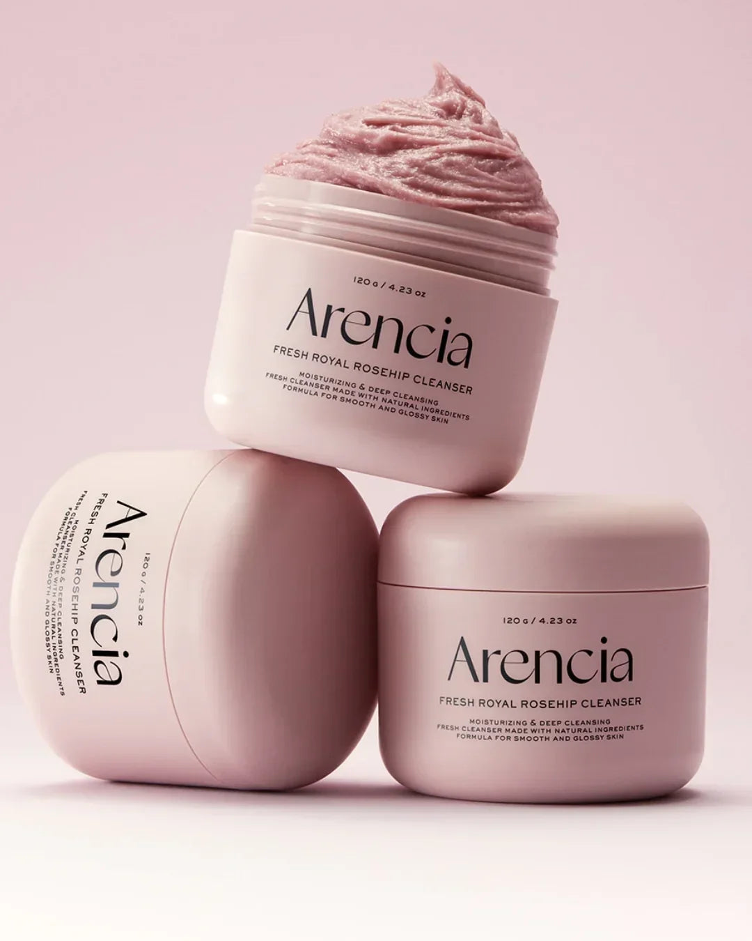 Three pink jars of Arencia Fresh Royal Rosehip Cleanser with creamy texture on soft pink background