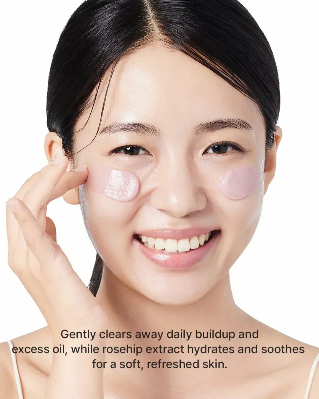 Smiling woman applying pink rosehip rice mochi cleanser on cheeks for hydrated soft skin