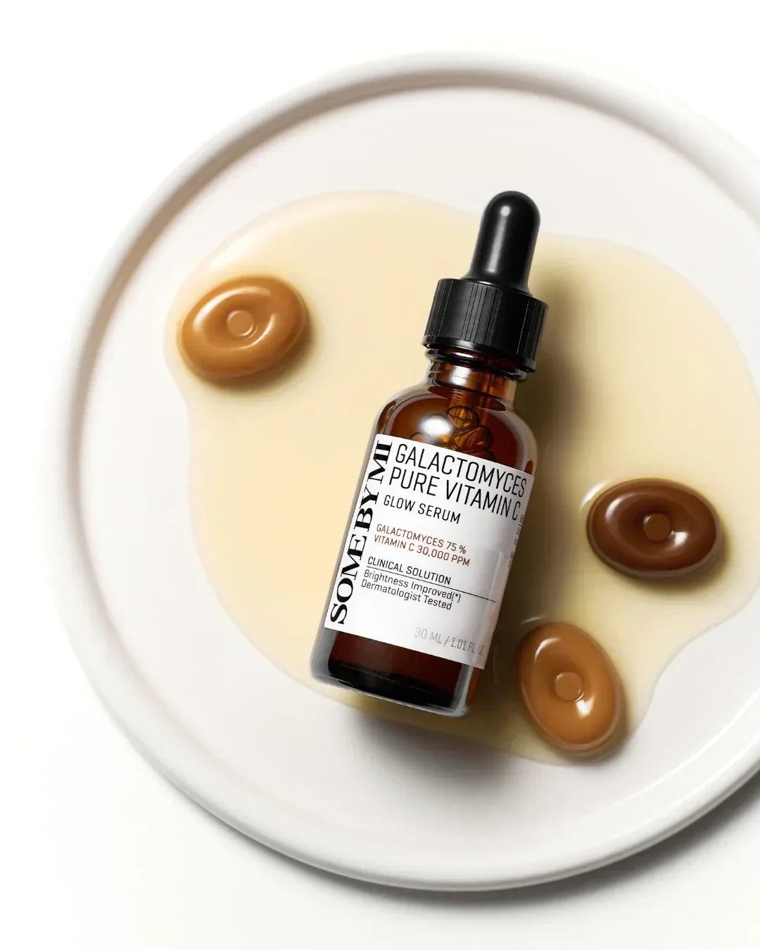 Some By Mi Galactomyces Pure Vitamin C Glow Serum bottle on white plate with serum drops