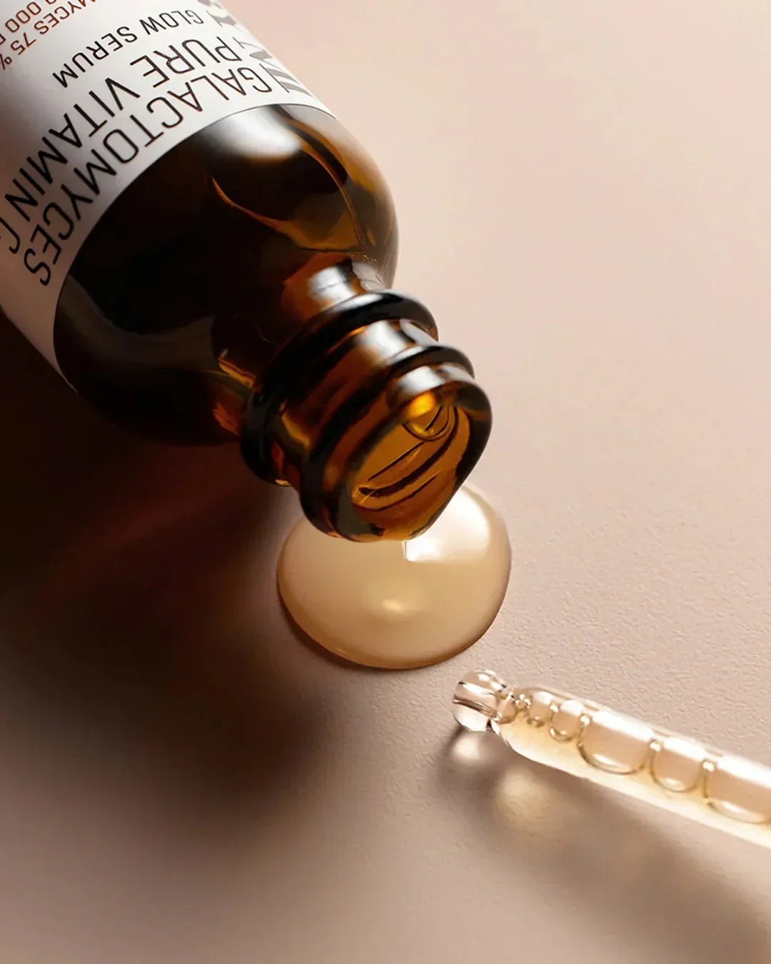 Galactomyces pure vitamin C glow serum bottle with dropper and spilled serum on beige surface
