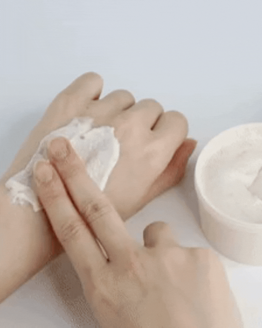 Applying white Ganghwa rice grain scrub cream on hand for exfoliating and moisturizing skin
