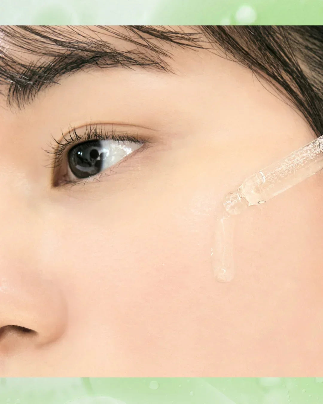 Close-up of woman with clear skin applying vitamin C serum with a dropper