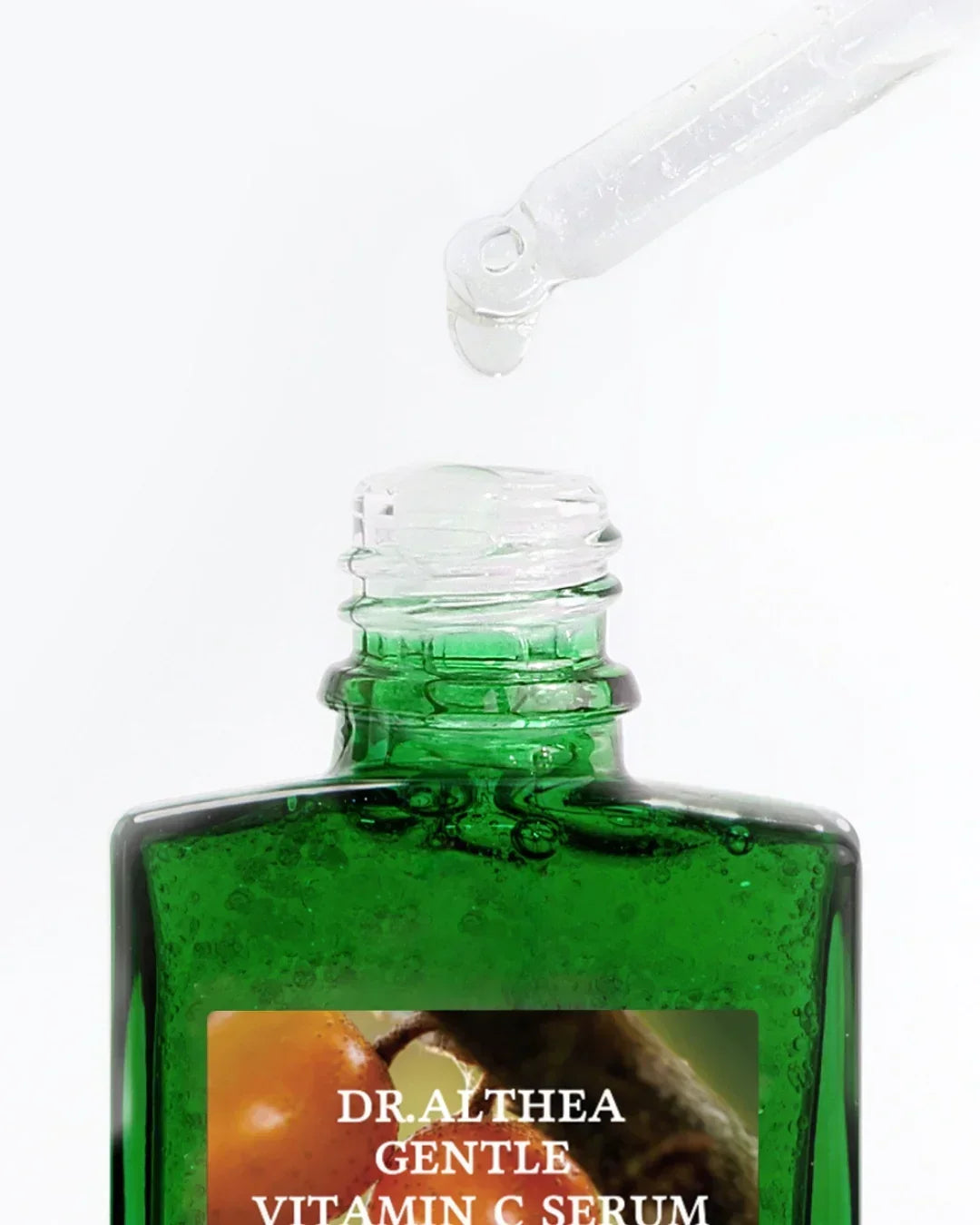 Green glass bottle of Dr. Althea Gentle Vitamin C Serum with dropper releasing clear serum