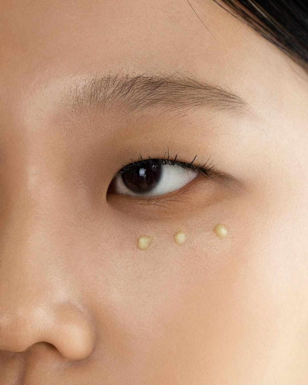 Close-up of eye with three drops of ginseng cleansing oil on smooth skin under eye