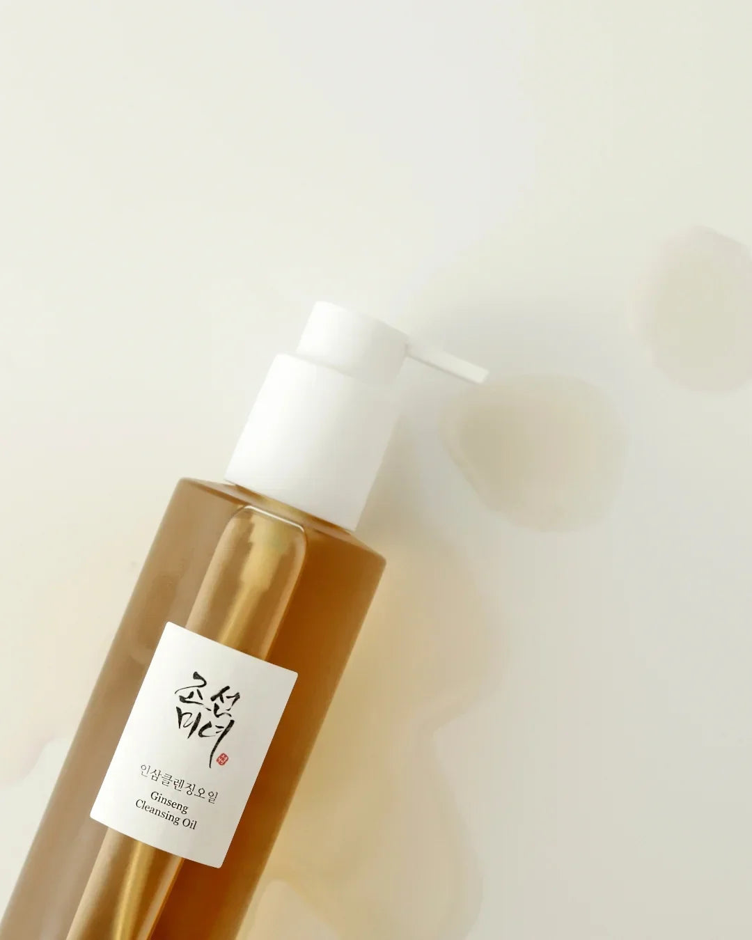 Amber bottle of ginseng cleansing oil with white pump dispenser on light background
