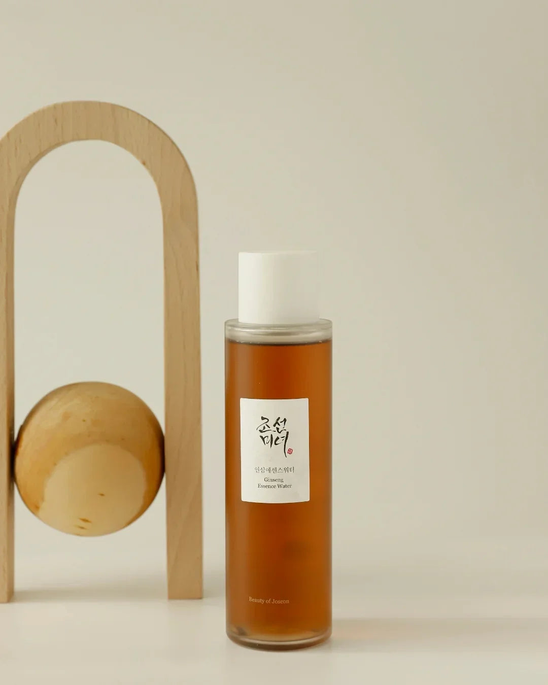 Ginseng Essence Water bottle with white cap and Korean label on white surface with wooden decor