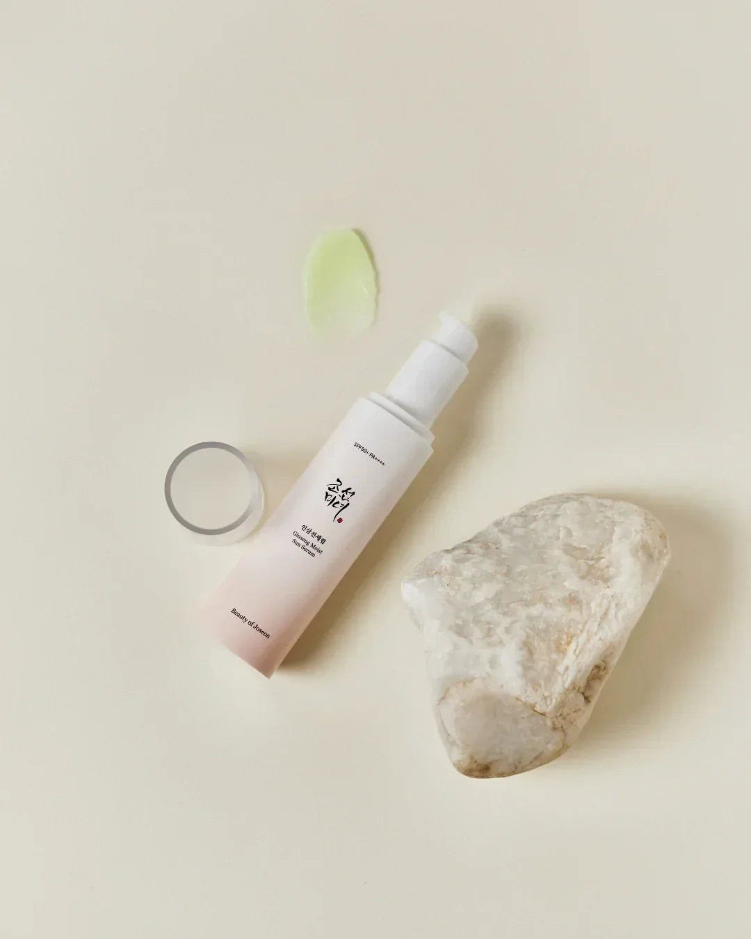 Ginseng Moist Sun Serum bottle with pump and product sample smear on beige background next to white stone