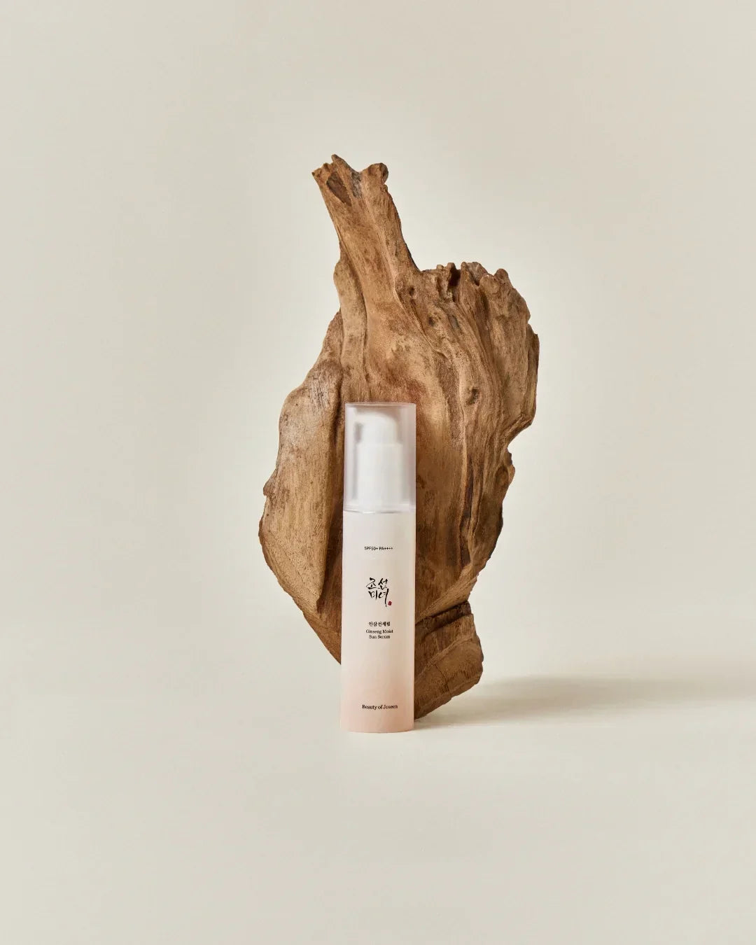 Ginseng Moist Sun Serum bottle with SPF50+ on wooden decorative piece on beige background