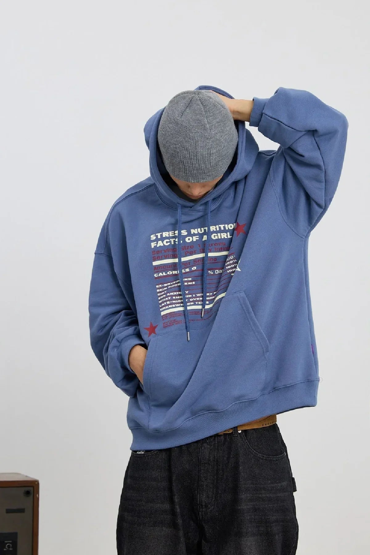 Person wearing dust blue hoodie with printed stress nutrition text and gray beanie