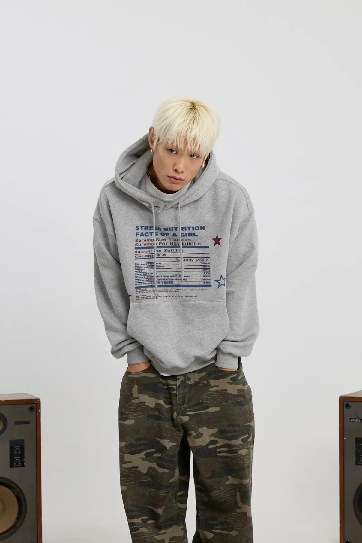 Young man with blonde hair wearing grey stress nutrition hoodie and camo pants in studio