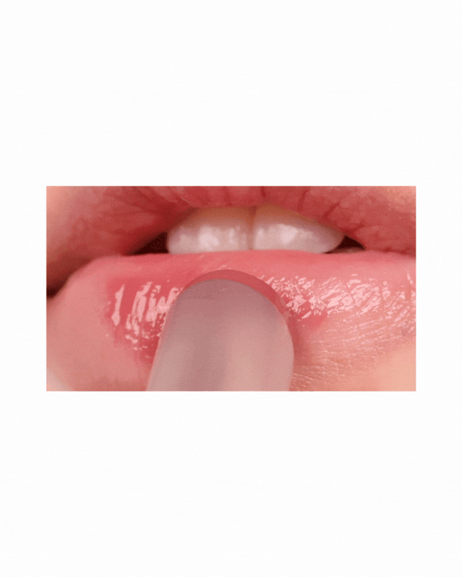Close-up of a person applying glossy melting balm on smooth lips with a fingertip